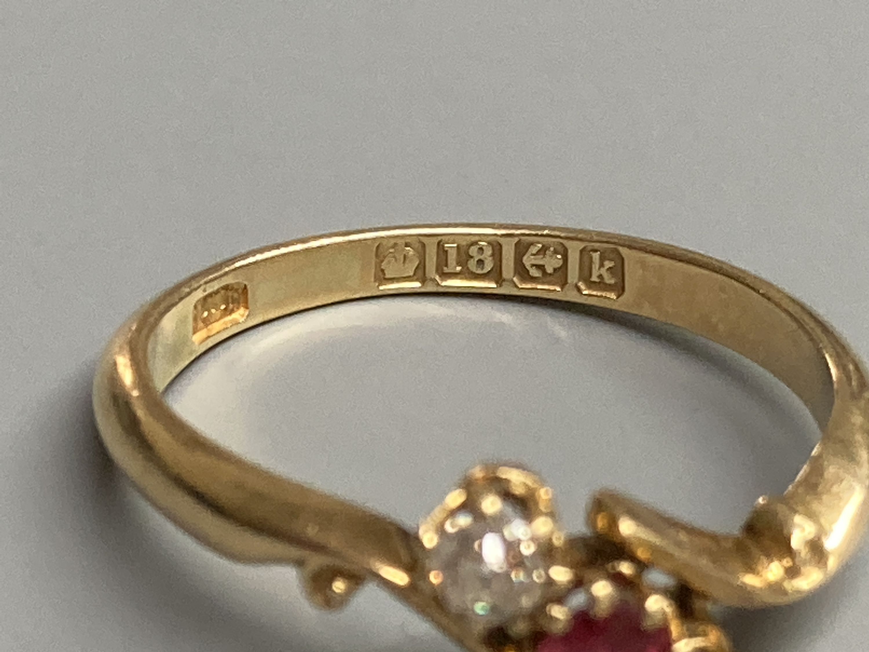 An Edwardian 18ct gold, red spinel and diamond set three stone crossover ring, size O, gross 2.9 grams